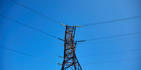 Tall power tower with wires stretches under clear sky