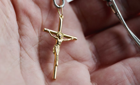 Gold cross pendant held in a hand with close up viewの写真素材