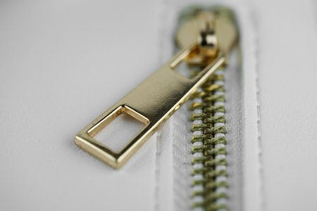 Close-up view of a gold zipper on white cloth.の写真素材