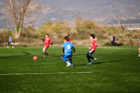Kids play soccer on a green field during afternoonの写真素材