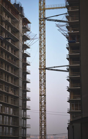 A crane towers between two buildings at twilight.