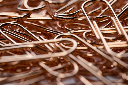 Abstract macro background showing a pile of shiny rose gold paper clipsの写真素材