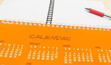 Plan for New Year, Orange Calendar with Pen and Notebook on Office Deskの写真素材