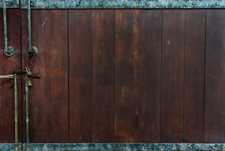 Closed Vintage Dark Brown Wooden Panel Door with Metal Line and Metal Button above and below with Rustic Metal Lock and Door Knob at The Corner as Copyspace used as Template to mock up or input Textの写真素材