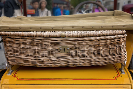 Old fashioned wicker basket on back of vintage car at country showの写真素材