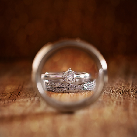 Bride's wedding and engagement rings photographed through the circle of the groom's ringの写真素材