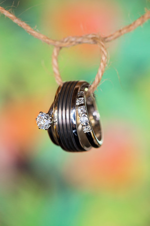 Bridal rings entwined with string, on a blurred green and yellow backgroundの写真素材