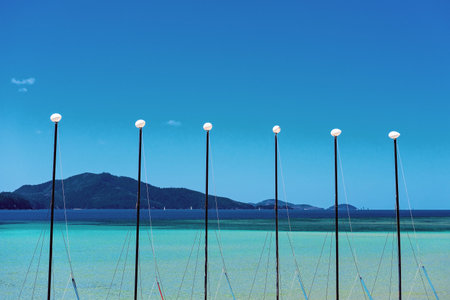 The rigging for masts on catamarans for hire on a tropical island form a pattern against the ocean...