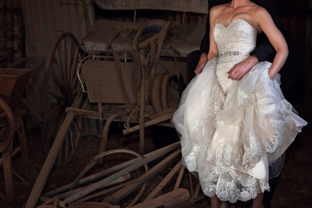 Bride and groom embrace in an old stables with vintage carriageの写真素材