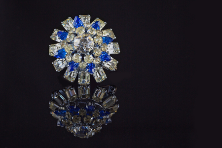 Vintage circular rhinestone broach with white and blue stones on black backgroundの写真素材