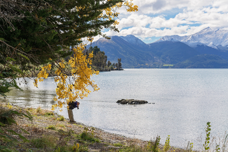 QUEENSTOWN, NEW ZEALAND - APRIL 2018: A photographer bending over to capture some of the many subjects on Lake Wakatipu New Zealand that attract photographers from all over the world, 18th April 2018.のeditorial素材