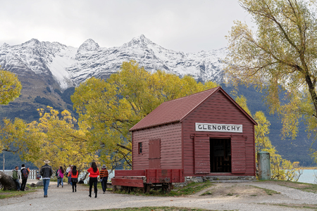 GLENORCHY, NEW ZEALAND - APRIL 2018: Tourists visiting the famed red hut at Glenorchy on the banks of Lake Wakatipu during autumn with snow covered alps in the background, 18th April 2018. This area attracts thousands of tourists every year.のeditorial素材