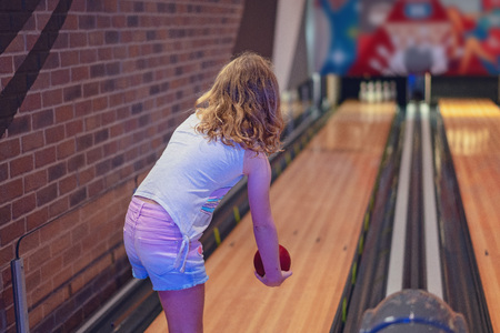 Young blond haired girl wearing shorts playing a game of indoor ten pin bowlsの写真素材