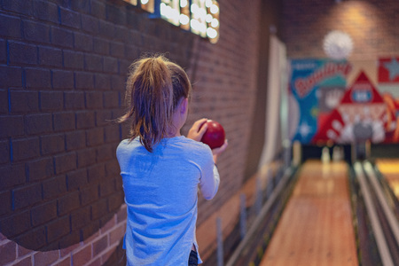 Young brown haired girl with pony tail playing a game of indoor ten pin bowlsの写真素材