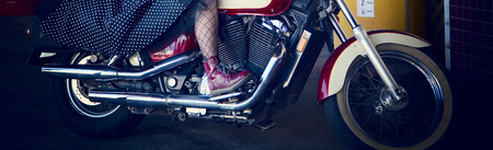Close up of a woman's leg encased in net stockings and wearing a red boot, riding a motorcycleの写真素材