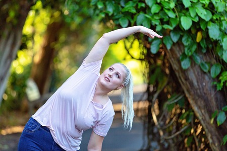 Blonde female exercising in park to lose weight and improve her lifestyleの写真素材
