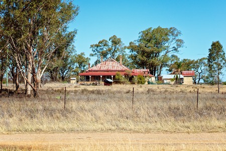 Road Trip - An old country homestead dilapidated and in need of repair stands alone on the roadsideの写真素材