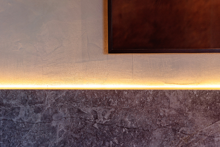 A photo frame on a painted wall above granite with a light strip glow - simplicity in shapesの写真素材