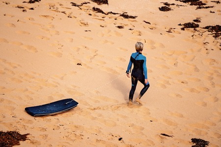 A surfer walks on the sand towards Bass Straight at Logan's Beach on The Great Ocean Road Australiaの写真素材