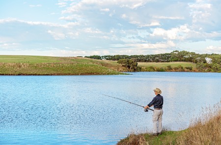 Male retiree fishing on the banks of the Hopkins River in Victoria Australiaの写真素材
