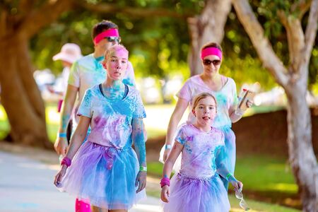 MACKAY, QUEENSLAND, AUSTRALIA - JUNE 2019: Two unidentified young girls covered in colored powder walk in Color Frenzy Fun Runのeditorial素材