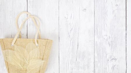Hessian bag covered with transparent leaves flat lay timber backdrop with copy space for your textの写真素材