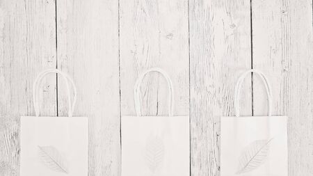 Three organic white paper disposable shopping bags on timber background with text copy spaceの写真素材