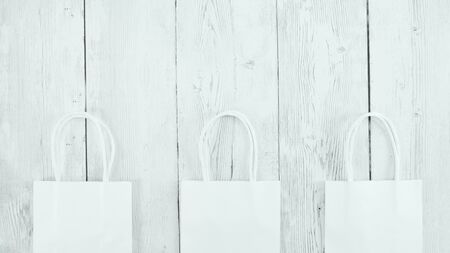 Three organic disposable paper shopping bags on rustic backdrop with text copy spaceの写真素材