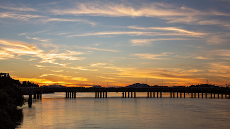 Darkness descends during the golden hour when the sun is setting in the night sky and the bridge and...
