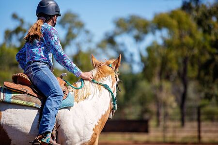 Close up of young girl equestrian sitting on her horse in a dusty outback country arena.の写真素材