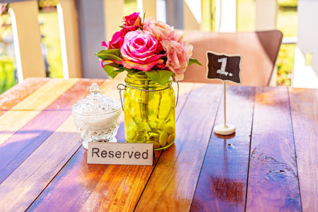 A reserved sign booking a table in a casual country cafe, with glass sugar bowl and vase of flowers...