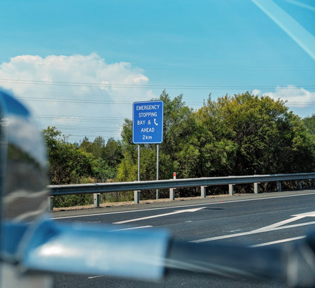 Emergency Stopping Bay sign with phone icon for use on a busy highway, seen framed by car side...