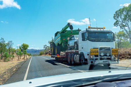 Clermont, Queensland, Australia - October 2019: A large truck transporting a car and farm machine as...
