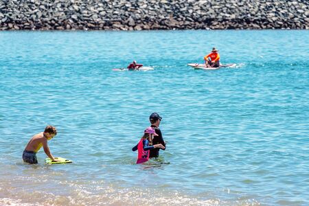 Mackay, Queensland, Australia - October 2019: People swimming and boarding in the ocean on a bright summery day at Harbour Beachのeditorial素材