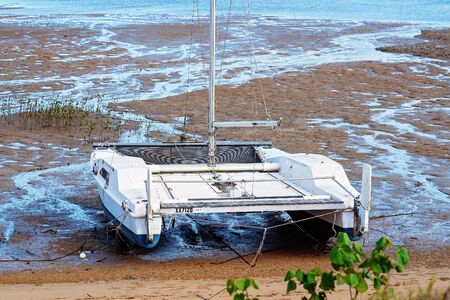 Mackay, Queensland, Australia - October 2019: Catamaran boat stranded on mud and sand up a creek at low tideのeditorial素材
