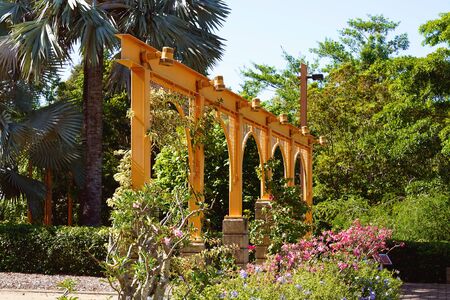 Arched decoration amongst landscaped botanic gardens on a bright sunny dayの写真素材