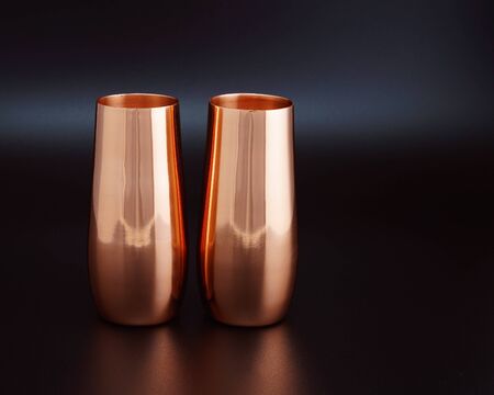 A pair of copper wine goblets burnished by soft lighting lit against a black backgroundの写真素材