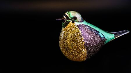 Colourful and artistically created glass bird against a black backgroundの写真素材