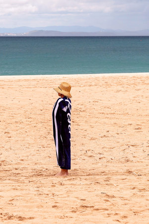 Yeppoon, Queensland, Australia - December 2019: A woman wearing a straw hat stands wrapped in a...