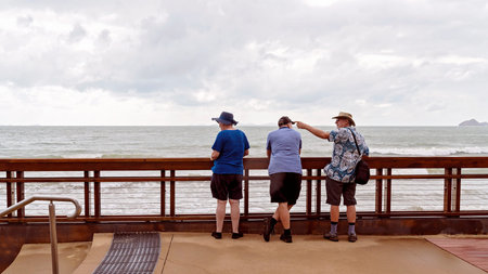 Yeppoon, Queensland, Australia - December 2019: Three holidaymakers watching the stormy sea at full...