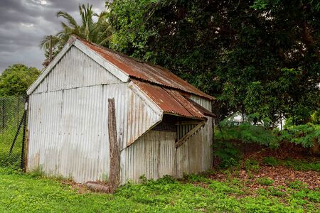 Old corrugated iron shed with push out windows in a lush green gardenの写真素材