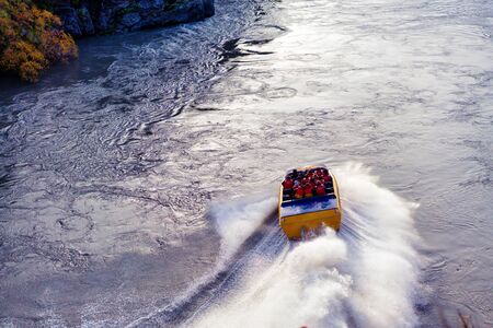 Tourists on Kawarau River jet boat adrenalin thrill riding through the canyon in New Zealandの写真素材