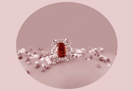 Garnet and diamond solitaire ring highlighted in a circle against a pink monotone backgroundの写真素材
