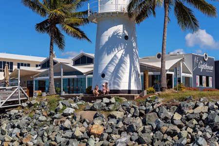 Mackay, Queensland, Australia - June 2020: A family sitting in front of a lighthouse watching boats in the marinaのeditorial素材
