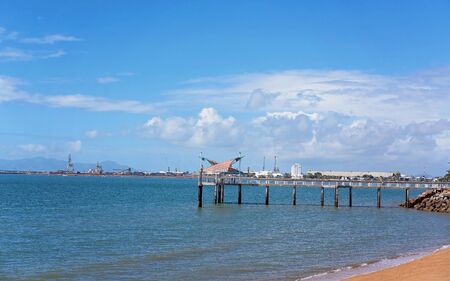 A jetty jutting out onto the water and used by the public for fishing and recreational activities, with an industrial wharf in the backgroundの写真素材