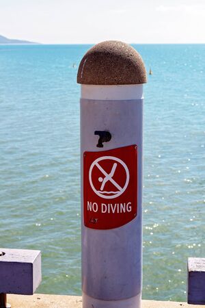 Close up of a no diving sign on a public jetty due to danger with ocean tidal depthsの写真素材
