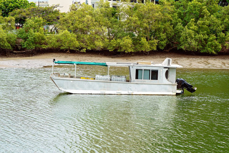 A vintage aluminium tin boat barge with modern outboard motor anchored on the river with its cargo
