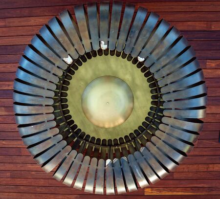 Huge and unusually shaped metal ceiling light against a timber roofの写真素材