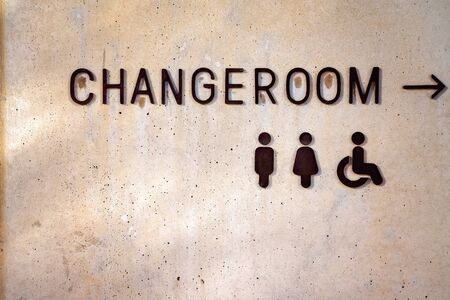Change Room sign with icons and arrow on a pitted concrete wallの写真素材