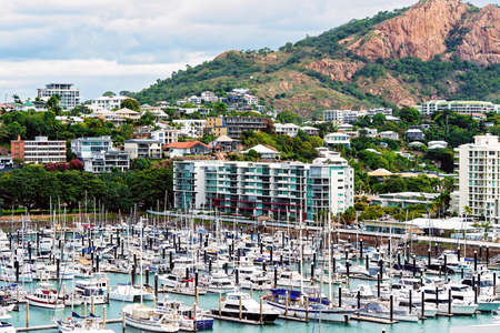 Townsville, Queensland, Australia - June 2020: Leisure boats berthed at a marina in the city surrounded by residential properties and with the pink granite monolith in the backgroundのeditorial素材